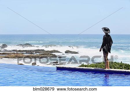 Mixed race woman walking by infinity pool View Large Photo Image Stock Photo - Mixed race woman walking by infinity pool. Fotosearch