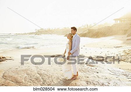 Picture - Newlywed couple hugging on beach. Fotosearch