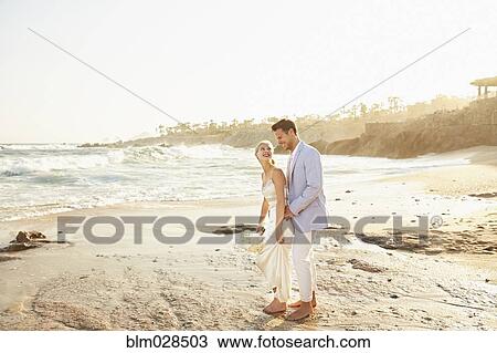 Stock Image - Newlywed couple hugging on beach. Fotosearch