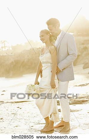 Newlywed couple hugging on beach View Large Photo Image Stock Photography - Newlywed couple hugging on beach. Fotosearch
