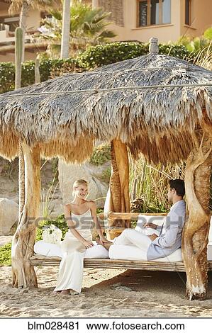 Newlywed couple relaxing in cabana View Large Photo Image Stock Image - Newlywed couple relaxing in cabana. Fotosearch