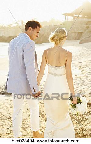 Picture - Newlywed couple walking on beach. Fotosearch