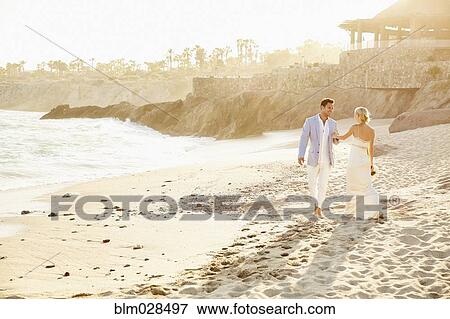 Newlywed couple walking on beach View Large Photo Image Stock Photo - Newlywed couple walking on beach. Fotosearch