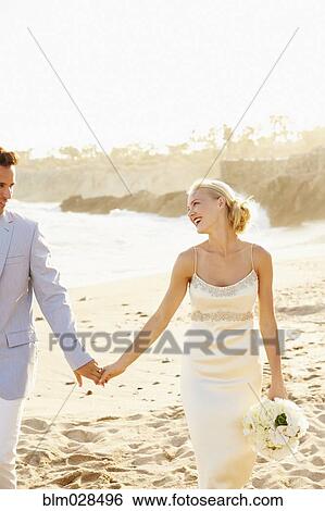Stock Photograph - Newlywed couple walking on beach. Fotosearch