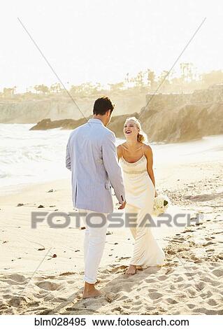 Stock Photography - Newlywed couple walking on beach. Fotosearch
