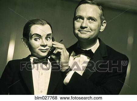 Performer holding cell phone to ventriloquist dummy View Large Photo Image Stock Photo - Performer holding cell phone to ventriloquist dummy. Fotosearch