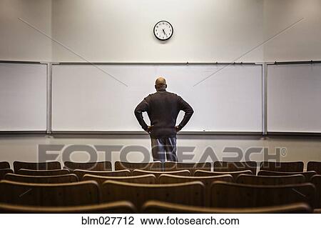 Stock Image - Professor standing in empty classroom. Fotosearch