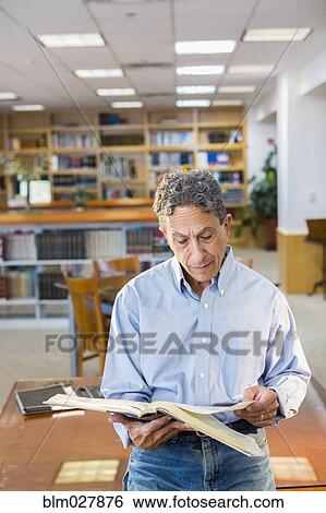 Stock Photograph - Senior man reading in library. Fotosearch
