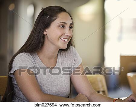 Smiling woman sitting at desk View Large Photo Image Picture - Smiling woman sitting at desk. Fotosearch