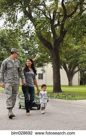 Stock Image - Soldier and family walking on suburban street. Fotosearch