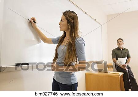 Stock Photograph - Student writing on whiteboard in classroom. Fotosearch