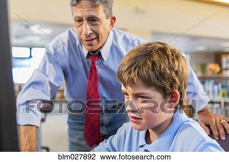 Stock Image - Teacher and student working at computer. Fotosearch