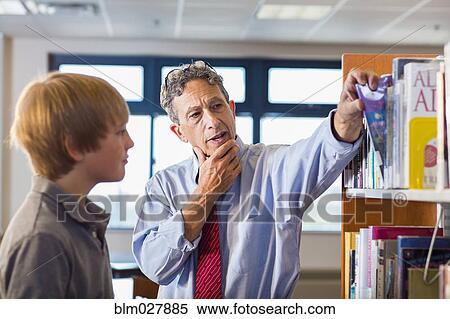 Stock Photography - Teacher and student working in library. Fotosearch
