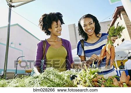 Stock Photograph - Women shopping together at vegetable stand. Fotosearch