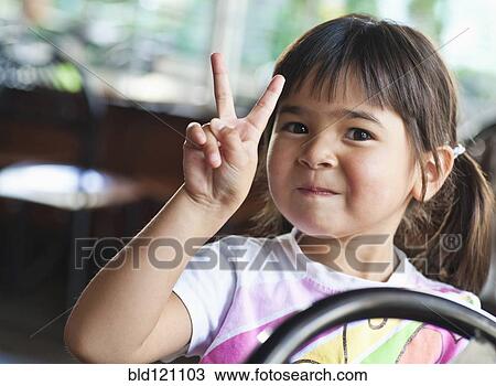 Stock Image - Asian girl making peace sign. Fotosearch