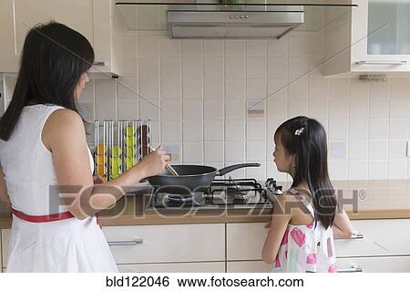 Stock Photograph - Asian mother and daughter cooking together. Fotosearch