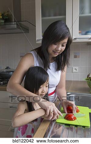 Stock Image - Asian mother and daughter cutting vegetables. Fotosearch