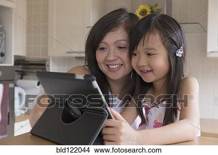 Asian mother and daughter using digital tablet View Large Photo Image Picture - Asian mother and daughter using digital tablet. Fotosearch