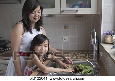 Asian mother and daughter washing vegetables View Large Photo Image Stock Image - Asian mother and daughter washing vegetables. Fotosearch