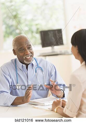 Stock Photograph - Black doctor and patient talking in office. Fotosearch