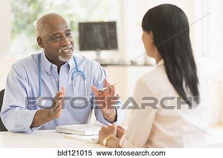 Stock Photography - Black doctor and patient talking in office. Fotosearch