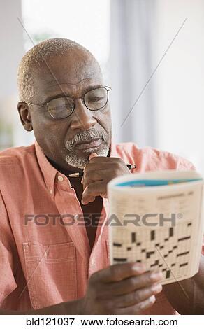 Stock Photo - Black man doing crossword puzzle. Fotosearch