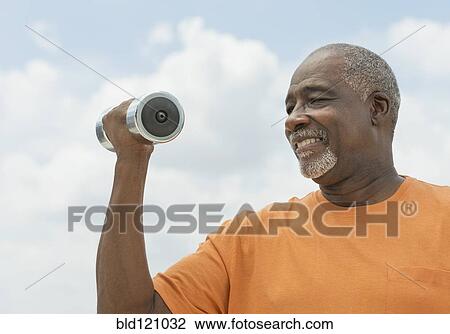 Stock Image - Black man lifting weights outdoors. Fotosearch