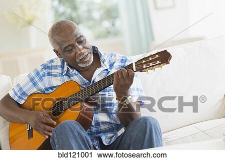 Black man playing guitar on sofa View Large Photo Image Stock Image - Black man playing guitar on sofa. Fotosearch