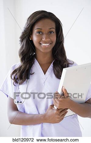 Stock Image - Black nurse carrying clipboard. Fotosearch