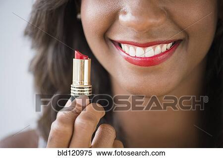 Stock Photography - Black woman holding lipstick. Fotosearch