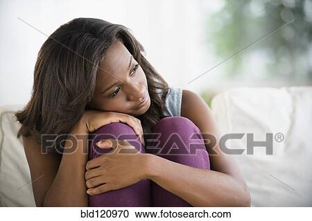 Stock Image - Black woman hugging her knees. Fotosearch