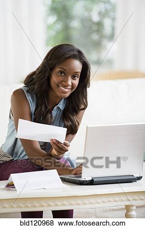Stock Photo - Black woman paying bills online. Fotosearch