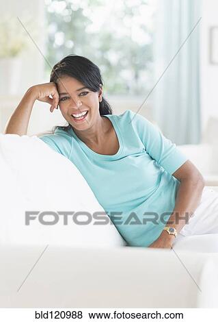 Stock Photo - Black woman smiling on sofa. Fotosearch