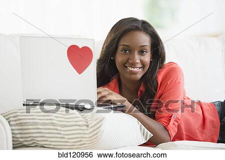 Black woman using laptop on sofa View Large Photo Image Stock Photograph - Black woman using laptop on sofa. Fotosearch