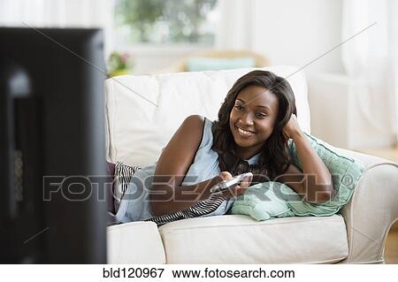 Black woman watching television on sofa View Large Photo Image Stock Photo - Black woman watching television on sofa. Fotosearch