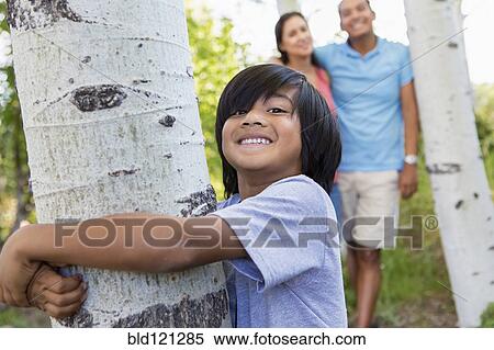 Stock Photography - Boy hugging tree outdoors. Fotosearch