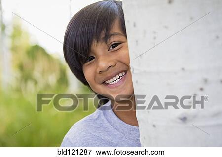 Boy peeking around tree outdoors View Large Photo Image Stock Photo - Boy peeking around tree outdoors. Fotosearch