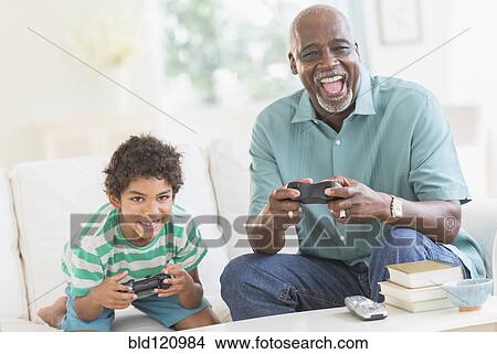 Boy playing video games with grandfather View Large Photo Image Picture - Boy playing video games with grandfather. Fotosearch