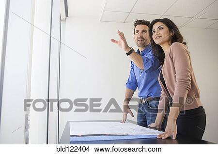 Picture - Business people examining blueprints in office. Fotosearch