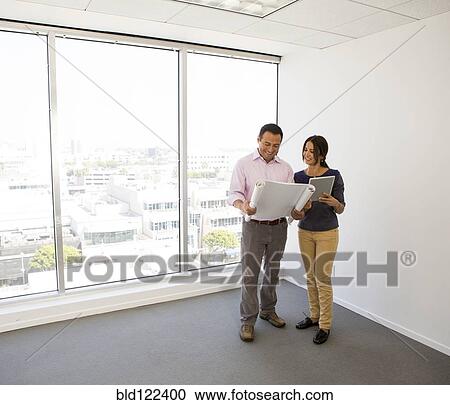 Business people examining blueprints in office View Large Photo Image Stock Image - Business people examining blueprints in office. Fotosearch
