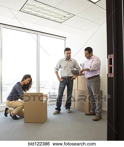 Stock Photograph - Business people unpacking in new office. Fotosearch