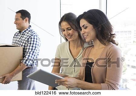 Businesswomen using digital tablet in office View Large Photo Image Stock Photograph - Businesswomen using digital tablet in office. Fotosearch