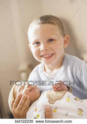 Stock Photography - Caucasian boy holding newborn baby brother. Fotosearch