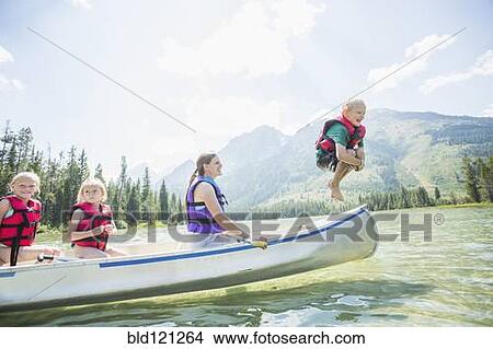 Picture - Caucasian boy jumping from canoe into lake. Fotosearch