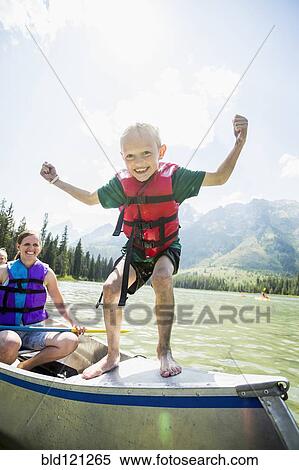 Stock Photography - Caucasian boy standing on canoe on lake. Fotosearch