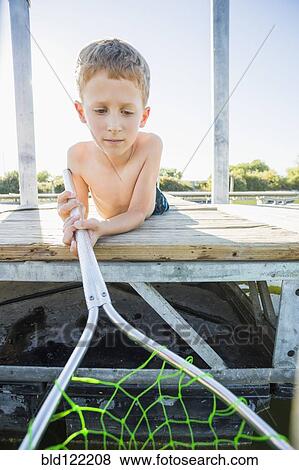 Stock Photo - Caucasian boy using fishing net on dock. Fotosearch