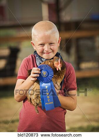 Stock Image - Caucasian boy with prize winning chicken on farm. Fotosearch