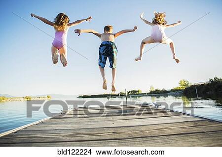 Caucasian children jumping off dock into lake View Large Photo Image Picture - Caucasian children jumping off dock into lake. Fotosearch