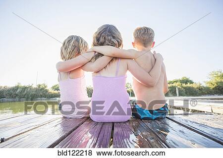Caucasian children sitting on dock View Large Photo Image Stock Photo - Caucasian children sitting on dock. Fotosearch