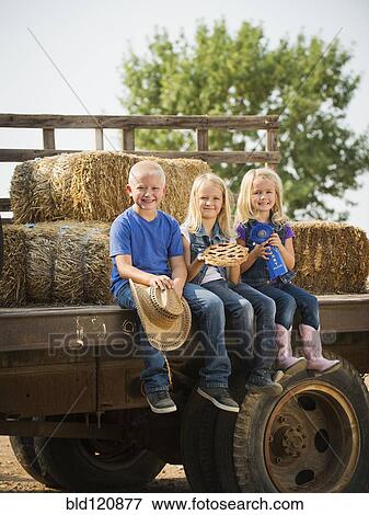 Stock Photo - Caucasian children sitting on truck on farm. Fotosearch